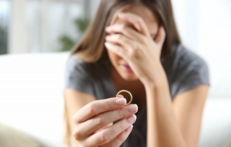 Woman holding back tears while holding a ring after a separation